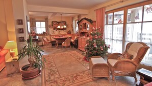 Una sala acogedora con un árbol de Navidad, muebles de mimbre y un comedor con una araña.