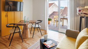 En moderne stue med et træspisebord, to stole, en sofa og et TV ophængt på væggen.