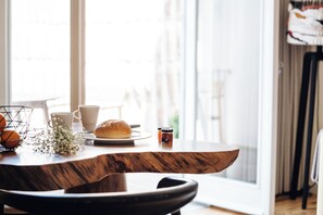 Een eettafel met een broodje, een kopje en een potje jam.