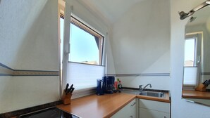 Eine kleine Küche mit Herd, Spüle und Fenster.