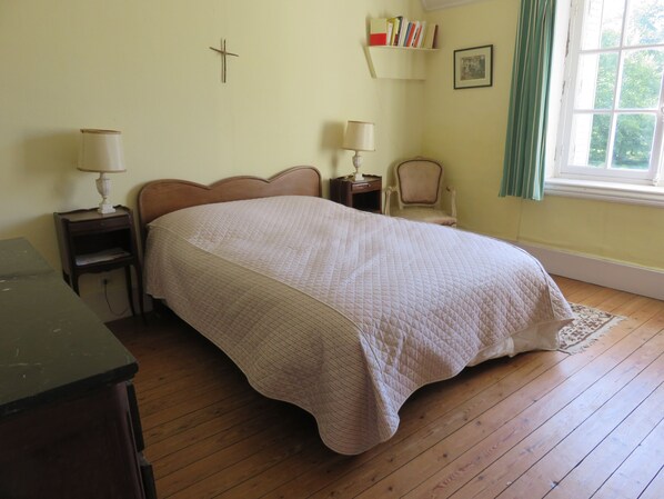 A bedroom with a bed, two bedside tables with lamps, a chair, a bookshelf, and a window with curtains. - Large house in private park, walking distance to the sea, sleeps 15 (Tréflez)