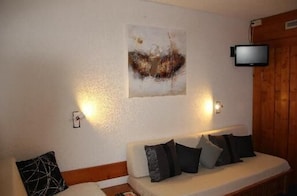 Relax in a cozy room with a sofa, pillows, and a large abstract painting, perfect for unwinding.
