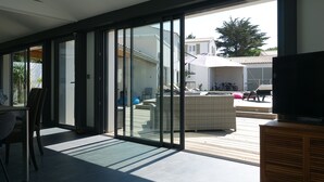 Uma sala de estar moderna com uma ampla porta de vidro deslizante que dá para uma área de varanda externa.