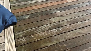 Um deck de madeira com um tecido azul no lado esquerdo.
