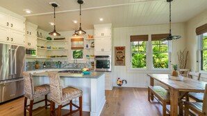 A kitchen with white cabinets, a wooden island, and a dining area with a wooden table and chairs.