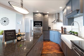 A modern kitchen with granite countertops, stainless steel appliances, and blue cabinetry. - Lake Michigan Home with gorgeous views, great spot for family or golf retreat (Sheboygan)