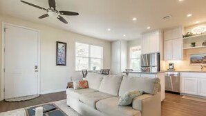 A modern living room with a beige sofa, a coffee table, and a ceiling fan. - VIEWS! Texas Hill Country - Bella Vista (Dripping Springs)