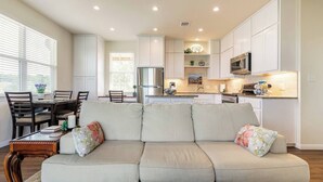 A modern kitchen with white cabinets, a stainless steel refrigerator, and a microwave. - VIEWS! Texas Hill Country - Bella Vista (Dripping Springs)