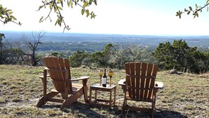 Two wooden Adirondack chairs facing a scenic view of a valley with trees and a distant horizon. - VIEWS! Texas Hill Country - Bella Vista (Dripping Springs)