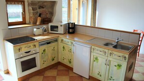 A compact kitchen with a stove, microwave, toaster, coffee maker, and sink.