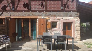 An outdoor patio with a table and chairs, a wooden door with heart-shaped cutouts, and a stone wall.