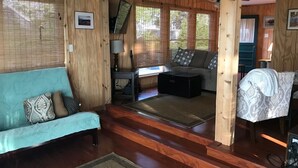 A wooden interior with a sofa, a coffee table, and a TV on a stand.
