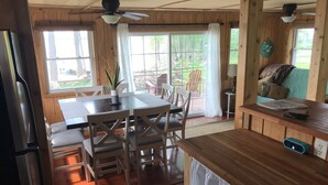 A wooden interior with a dining table, chairs, ceiling fans, and a view of the outdoors.