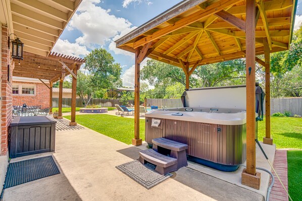 Un patio exterior con un jacuzzi, una zona de estar cubierta y una parrilla.