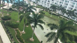 A resort with a pool, palm trees, and a well-maintained lawn. - Ocean and swimming front pool view, 6 persons, 2 bedrooms and 2 bathrooms (Bahia De Banderas, Nuevo Vallarta, Bucerias)