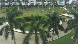 A multi-story hotel with a central courtyard surrounded by palm trees and a small pond. - Ocean and swimming front pool view, 6 persons, 2 bedrooms and 2 bathrooms (Bahia De Banderas, Nuevo Vallarta, Bucerias)