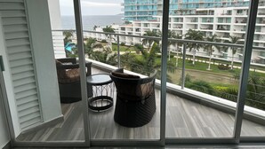 A balcony with a view of a hotel building, a pool, and palm trees. - Ocean and swimming front pool view, 6 persons, 2 bedrooms and 2 bathrooms (Bahia De Banderas, Nuevo Vallarta, Bucerias)