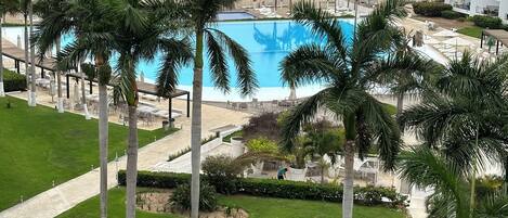 A resort with a pool, palm trees, and a view of the ocean.