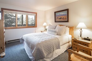 A bedroom with a large bed, two bedside lamps, a wooden dresser, and a painting on the wall. - Outpost: Nez Perce D6 - Hot Tub Access! (Teton Village)
