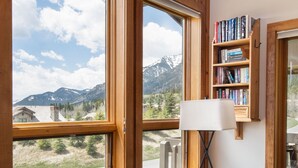 Un salon confortable avec une grande fenêtre, une bibliothèque et un canapé en cuir.
