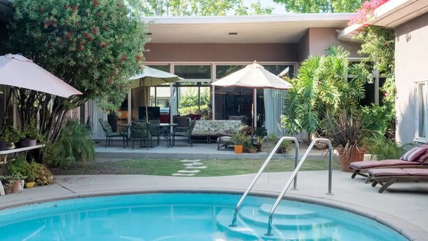 A backyard with a swimming pool, outdoor furniture, and potted plants. - Bixby Beauty 50s Mod -- Pool and Parking (Long Beach)