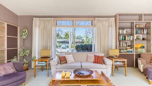 A living room with a sofa, coffee table, and a bookshelf. - Bixby Beauty 50s Mod -- Pool and Parking (Long Beach)