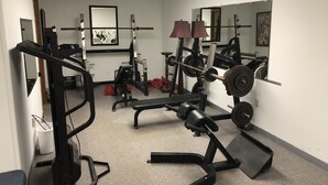 Un gimnasio con diverso equipo de ejercicio, que incluye máquinas de pesas y bancos.