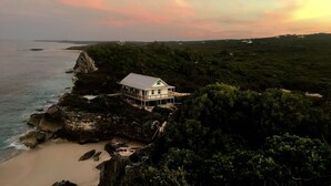 A coastal house with a balcony overlooking the sea, surrounded by lush greenery. - Spectacular Eco Cottage, oceanfront, secret beach (Gregorytown)