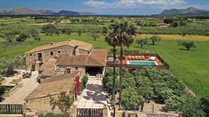 Uma villa com piscina, cercada por vegetação exuberante e montanhas ao fundo.