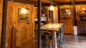 Un intérieur rustique comprenant un coin repas, des murs en bois, un ventilateur de plafond et une tête d’animal fixée au mur.
