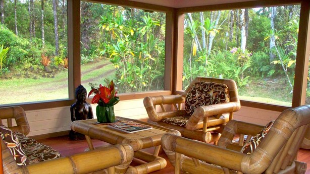 A room with bamboo furniture, a Buddha statue, and a view of a forest through large windows. -  Enchanting Rainforest Hideaway, on 2 Private Acres to yourself.  Pahoa/Keaau   (Pahoa)