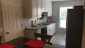 A kitchen with white cabinets, a black countertop, a red rug, and a window with blinds. - Cottage. 3 bedrooms, 2 baths and full kitchen on sheep and goat farm  (Jefferson)