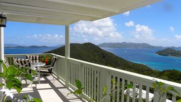 A balcony with a view of the sea and hills.