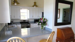 A kitchen with white cabinets, a stainless steel stove, a sink, and a wooden chair. - Brigadoon: A beautiful Villa In Red Hook sleeps 6 studio is available to rent 2 (St. Thomas)
