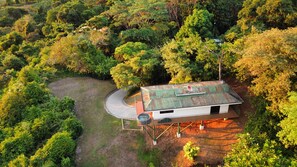 Vista aérea de una casa rodeada de un bosque frondoso, con un camino de entrada sinuoso.