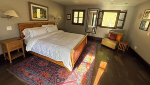 Un dormitorio con una cama grande, mesitas de noche, un sofá, un espejo y una ventana.