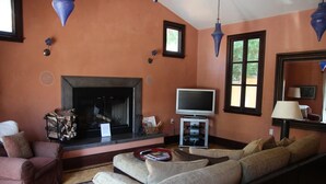 Una sala de estar con chimenea, televisor y sofá.