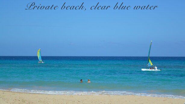 Ein privater Strand mit klarem, blauem Wasser und zwei Segelbooten.