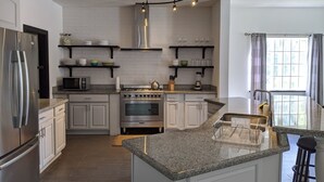 Eine moderne Küche mit weißen Schränken, einem Edelstahl-Kühlschrank, einem Einbauofen und einer Arbeitsplatte aus Granit.