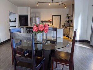 A dining area with a glass table, dark wooden chairs, and a vase of flowers.