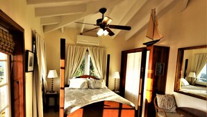 A bedroom with a bed, a chair, a table, and a ceiling fan. - The 'Cottage' at Lion's Gate - Check for our Spring & Summer Specials (Red Hook)