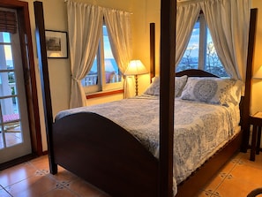 Un lit à baldaquin avec une couvre-lit à motifs, une lampe de chevet et des rideaux.