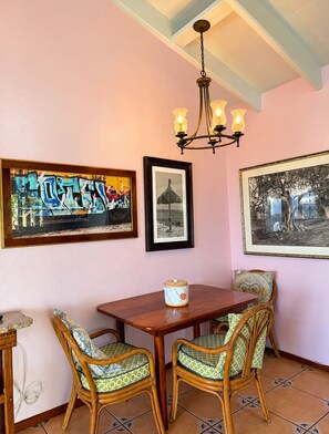 A dining area with a wooden table, wicker chairs, and a chandelier. - The 'Cottage' at Lion's Gate - Check for our Spring & Summer Specials (Red Hook)