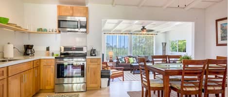 A modern kitchen with stainless steel appliances, wooden cabinets, and a dining area with a table and chairs.