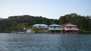 A row of three houses by a lake with a forested hill in the background. - !Romantic Getaway Or Small Family Fun Time! Hill View Cabins. (Jonesville)