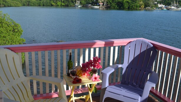 A deck with two chairs and a table, overlooking a lake with boats and greenery. - !Romantic Getaway Or Small Family Fun Time! Hill View Cabins. (Jonesville)