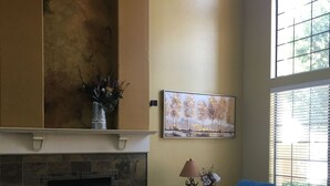 A living room with a fireplace, a sofa, a lamp, and a painting on the wall. - NEW! Luxury Lakefront Estate with Pool and Putting Greens (Glendale)
