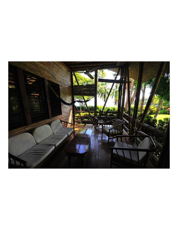 An outdoor seating area with a wooden structure, cushioned benches, and tables.