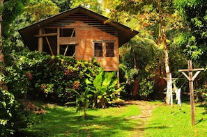 A rustic wooden house surrounded by lush greenery and a small garden.