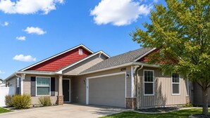 A two-story house with a red roof, beige siding, and a garage.